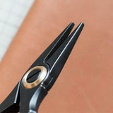 Stainless steel needle pulling pliers for leather hand stitching. Compact one-hand design with finger ring, spring-back jaw, and serrated flat tips to grip stuck needles through thick leather or tight stitch holes. Shop now.