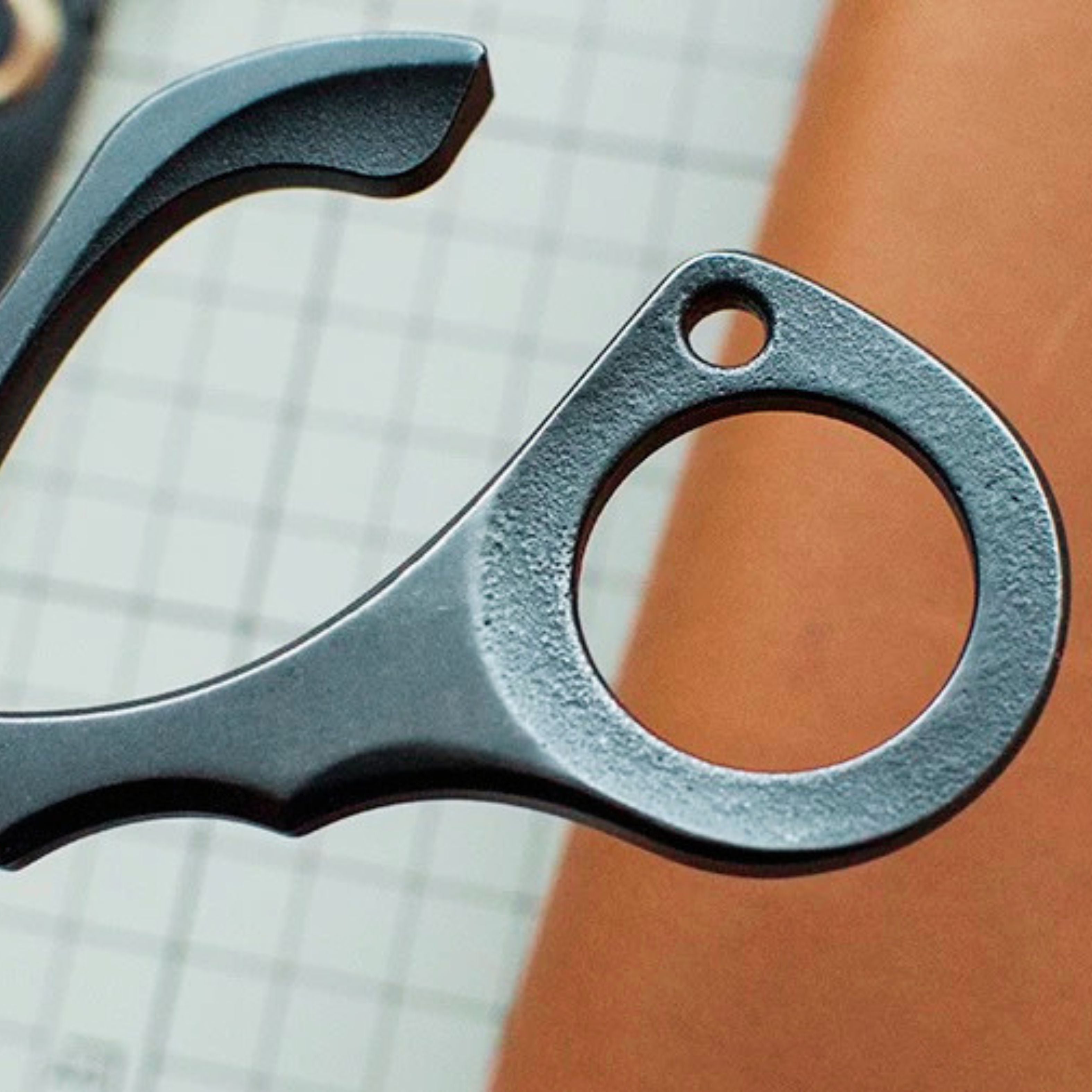 Stainless steel needle pulling pliers for leather hand stitching. Compact one-hand design with finger ring, spring-back jaw, and serrated flat tips to grip stuck needles through thick leather or tight stitch holes. Shop now.