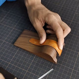 Black walnut strap molding tool with a fixed steel pin for secure strap hold. Simulates the natural wrist curve for more precise shaping.