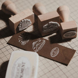 Custom wooden rubber stamp for leather, paper, cardboard, fabric, packaging, tags, and notebook covers. Made from your logo, text, or artwork, with a free Japanese ink pad included. Clean, handmade stamping for branding and packing. Send your design to get started.
