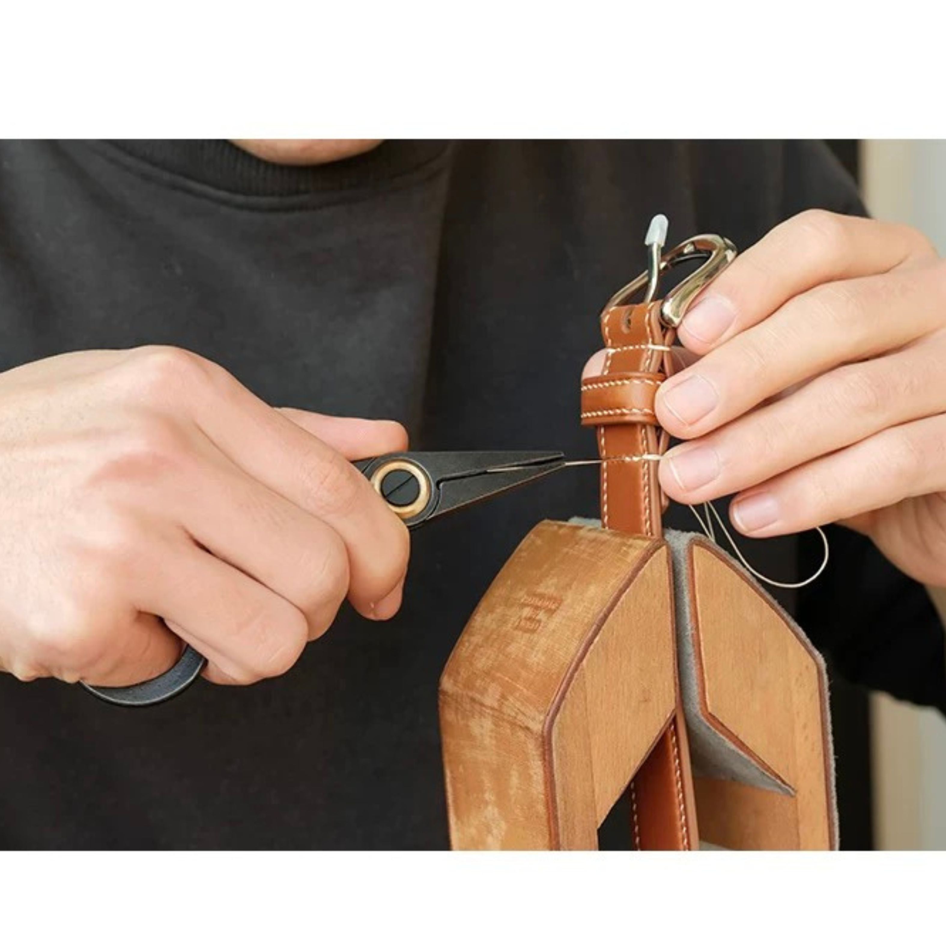 Stainless steel needle pulling pliers for leather hand stitching. Compact one-hand design with finger ring, spring-back jaw, and serrated flat tips to grip stuck needles through thick leather or tight stitch holes. Shop now.